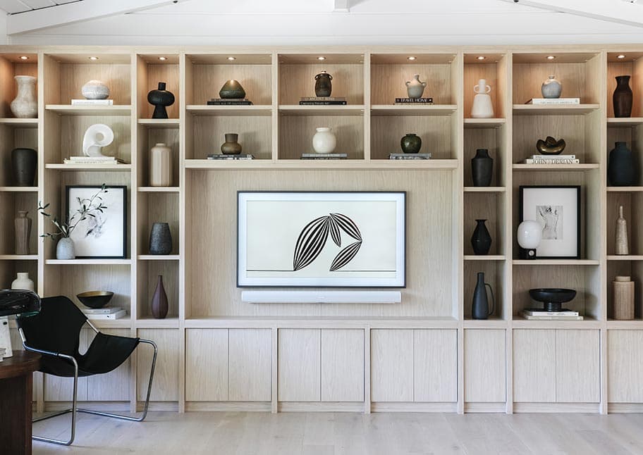 Centro de entretenimiento personalizado en un acabado clásico de madera blanca con estanterías y bancos creado por California Closets