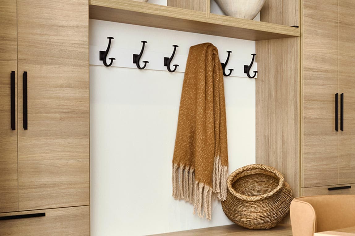 Accesorios de entrada con ganchos para abrigos, corbatas y cinturones diseñados por California Closets