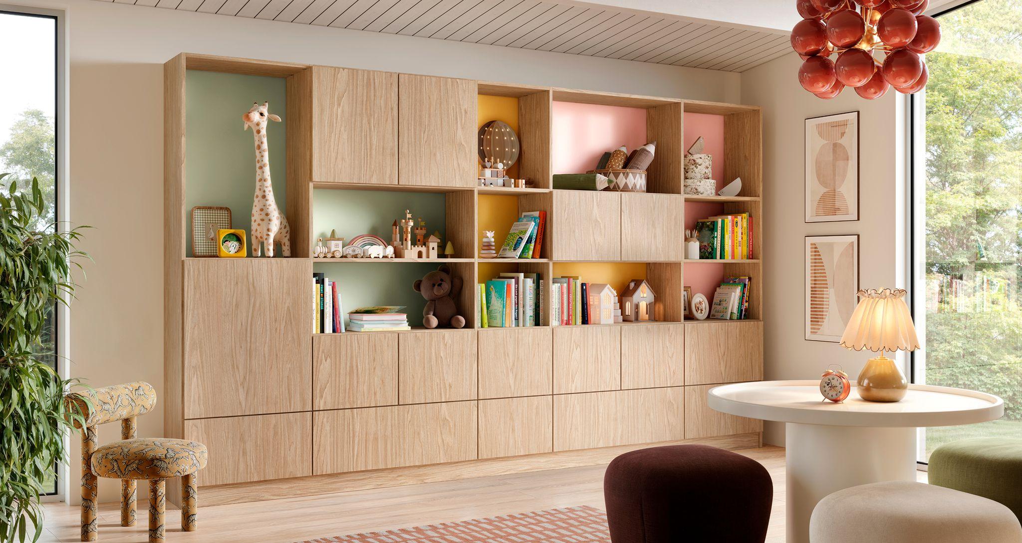 Unidad de pared personalizada de madera clara moderna con paneles de vidrio pintado por detrás en tonos pastel coloridos en una sala de juegos infantil o espacio creativo.