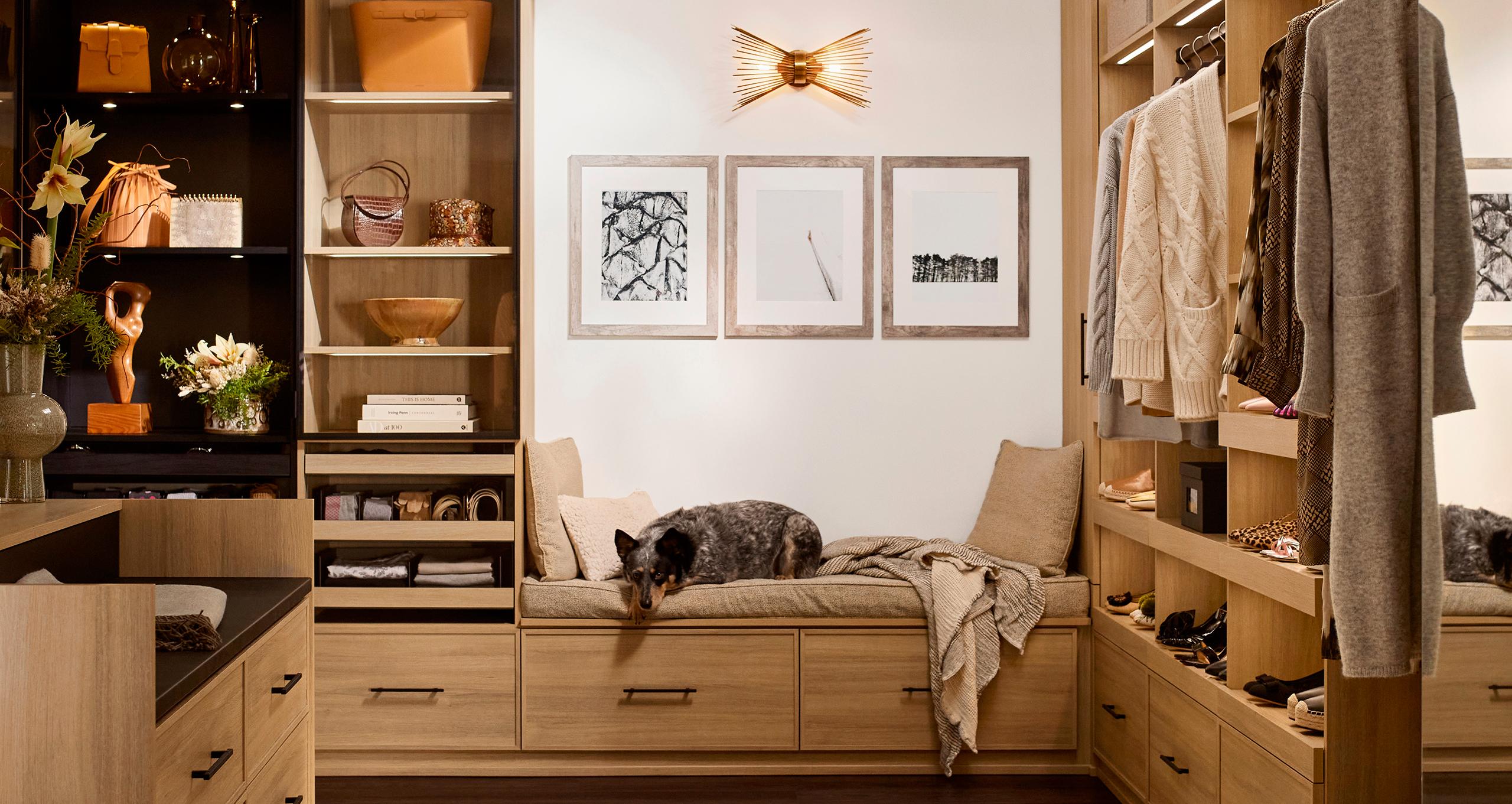 Clóset vestidor diseñado con estantes personalizados y banco con cama para perro de California Closets