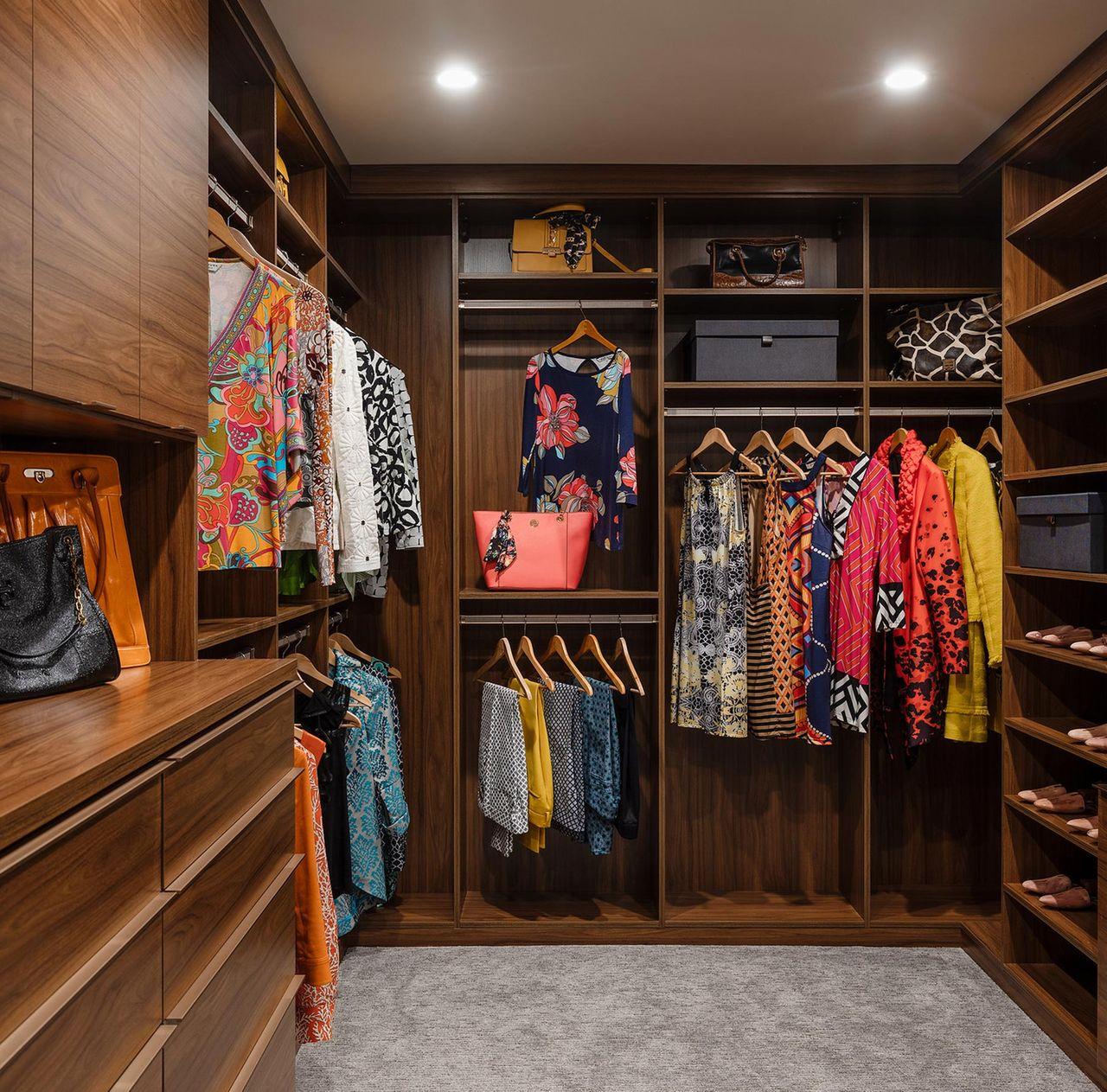 Armario personalizado en acabado de veta de madera marrón rojiza con almacenamiento de piso a techo por California Closets