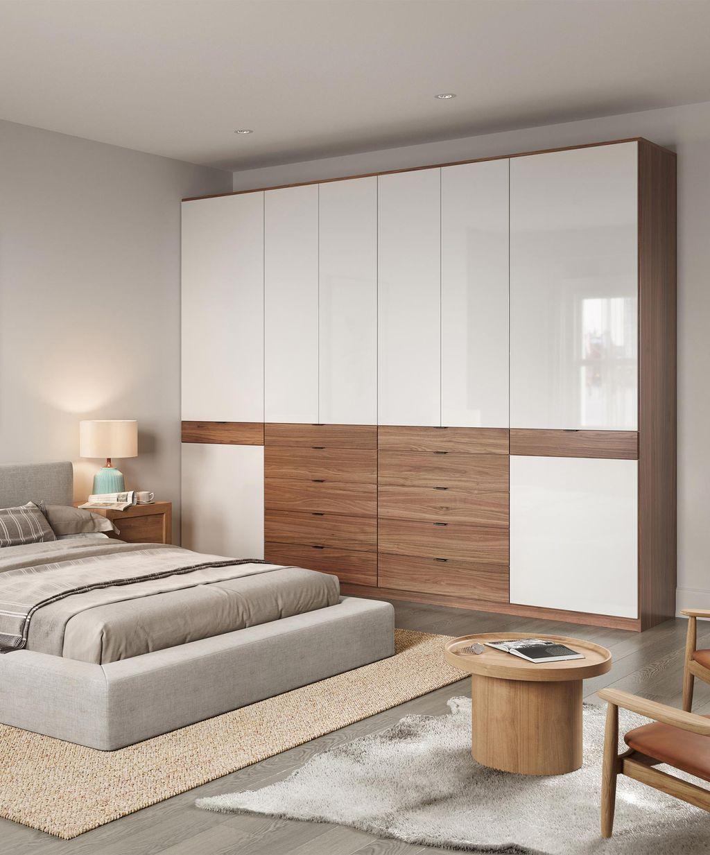 Armario personalizado empotrado en la pared, ropero independiente en acabados brillantes y de veta de madera clara por California Closets