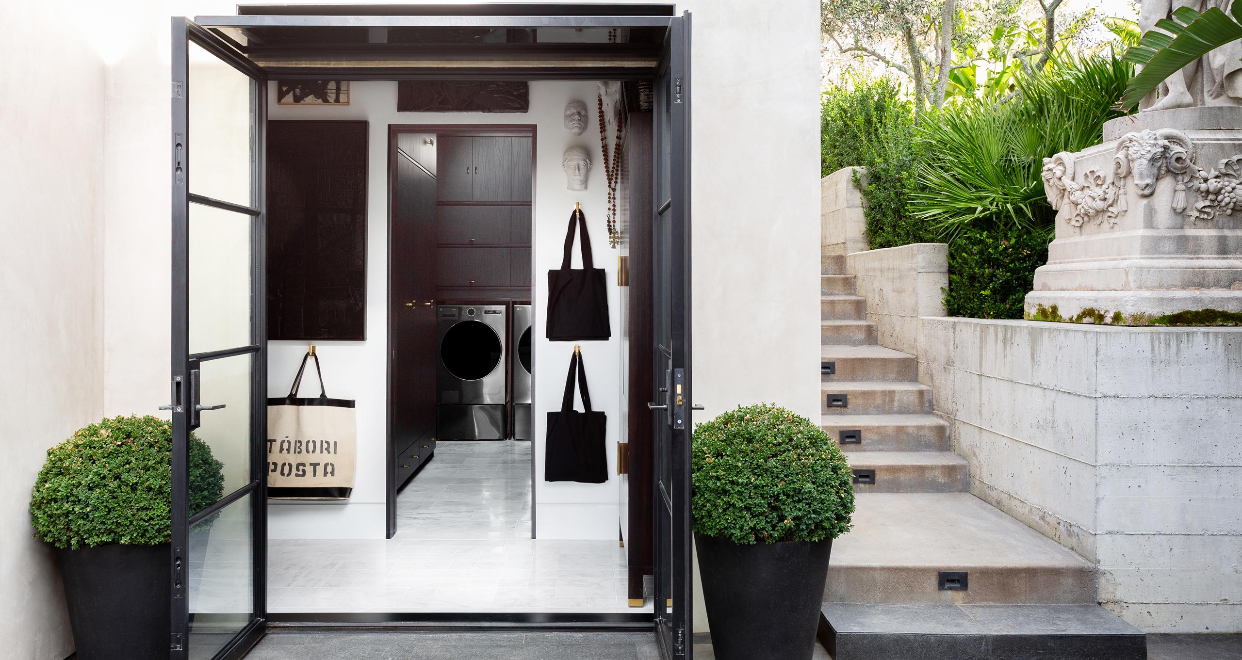 Beautiful laundry room designed with dark cabinets, marble surfaces and French doors from California Closets