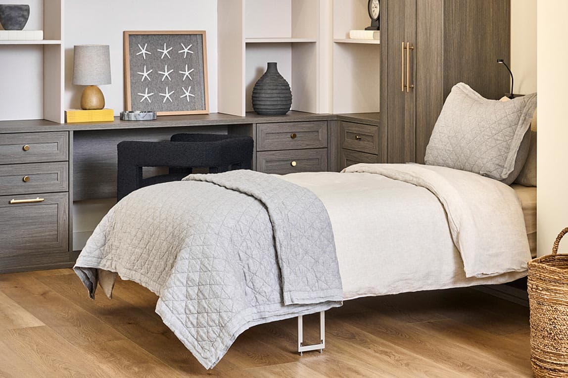 Customized murphy bed opened with workspace desk and custom shelving by California Closets