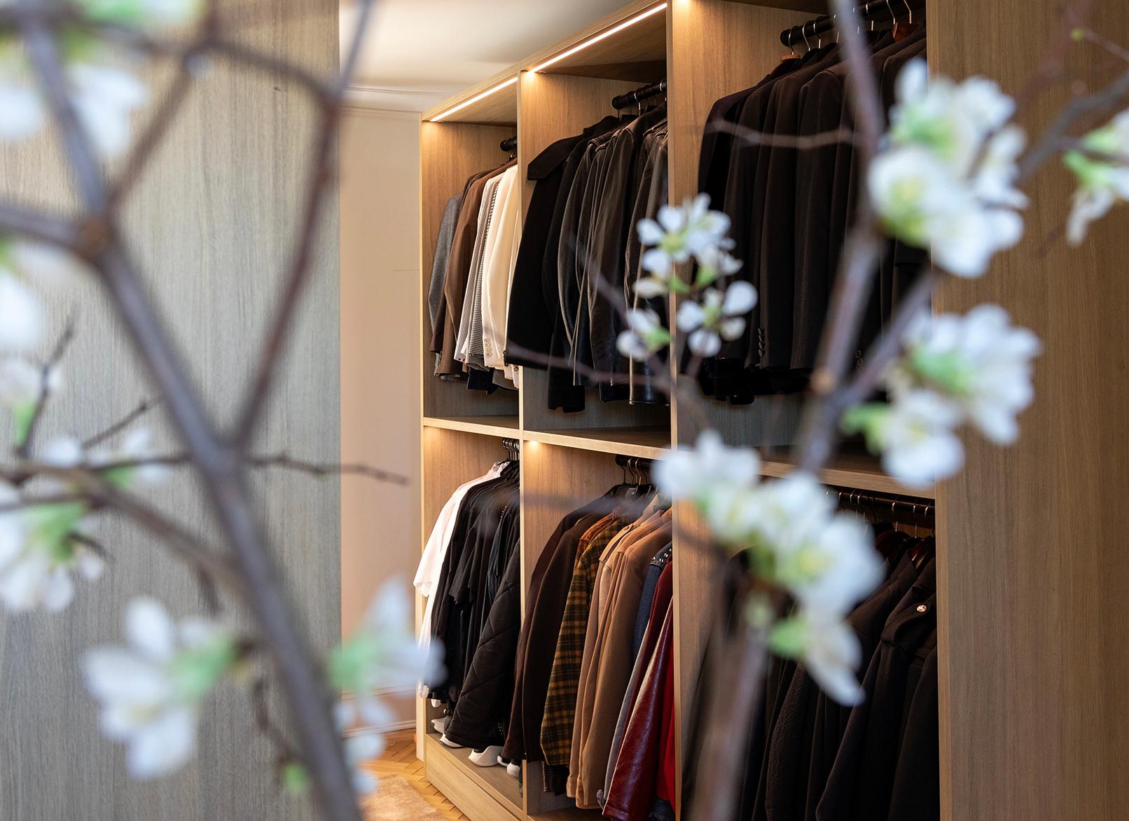 Vestidor con barras para colgar, iluminación y estantes abiertos de Jeremiah Brent y California Closets
