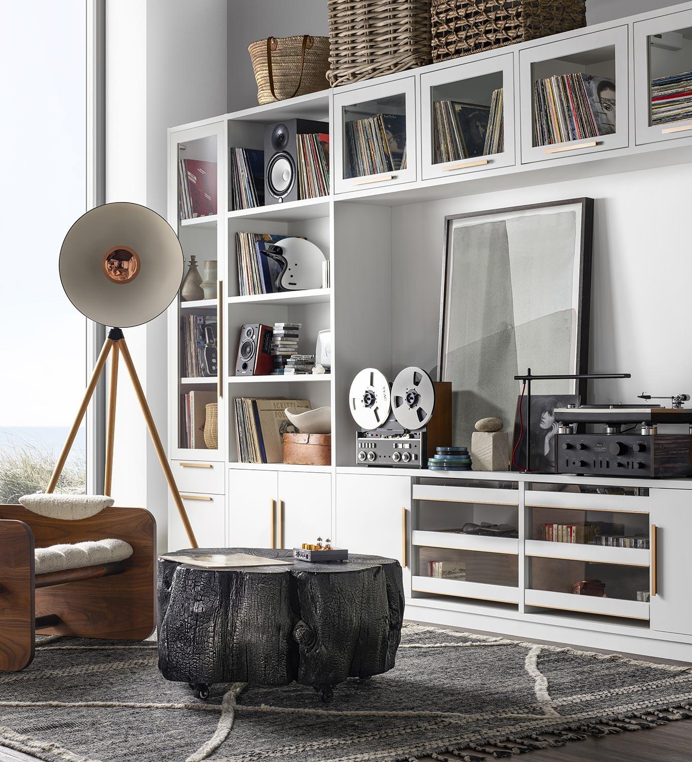 Espacio tipo loft con diseno retro, almacenamiento de medios personalizado y centro de entretenimiento con acabado en madera blanca por California Closets