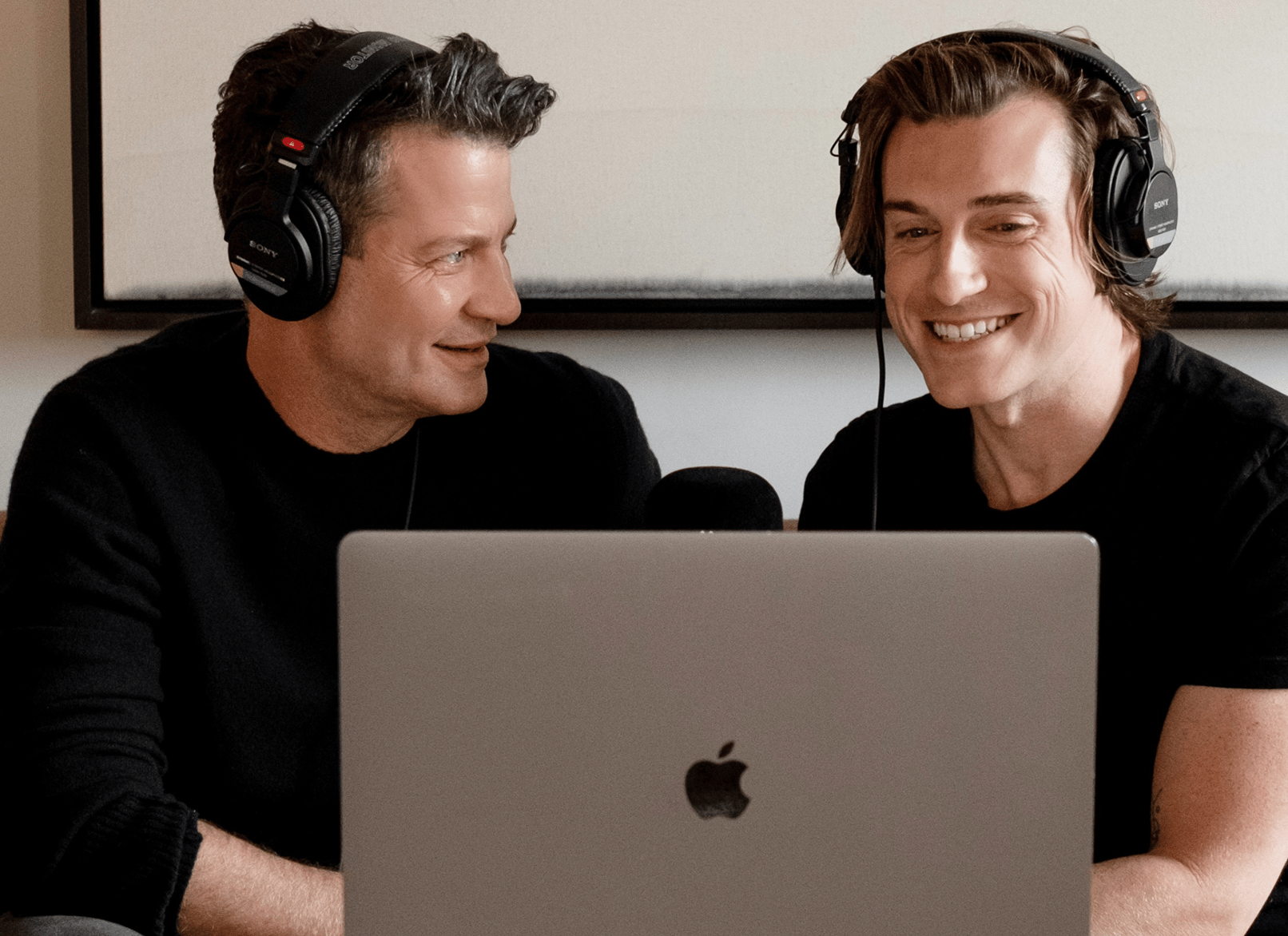 Jeremiah Brent grabando un episodio de podcast frente a una computadora portátil y un micrófono junto a un invitado para California Closets.